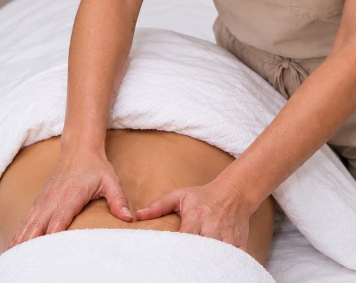 Selma's hands working across a draped client's abdomen during a session